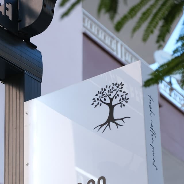 Shopfront sign carrying a hand-drawn tree logo