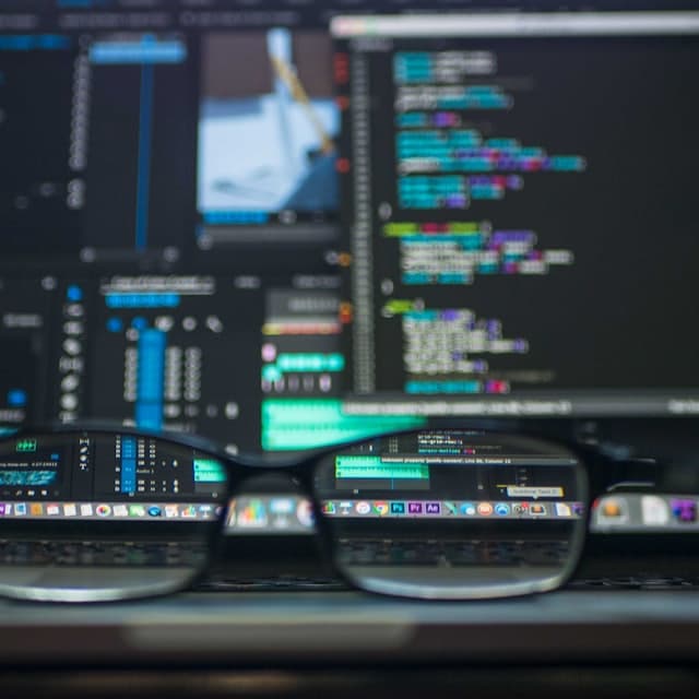 Glasses focusing a blurred editor full of code behind them